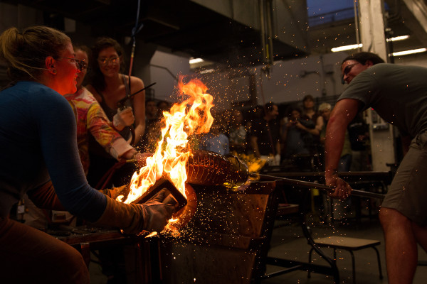 Image by Alec Miller. (Left to right) Glass Artist Kelly O’Dell blows an Ammonite, assisted by Patricia Davidson, Lydia Boss, and Raven Skyriver at the Pratt Open House, “One Hot Night,” Sept 7, 2013